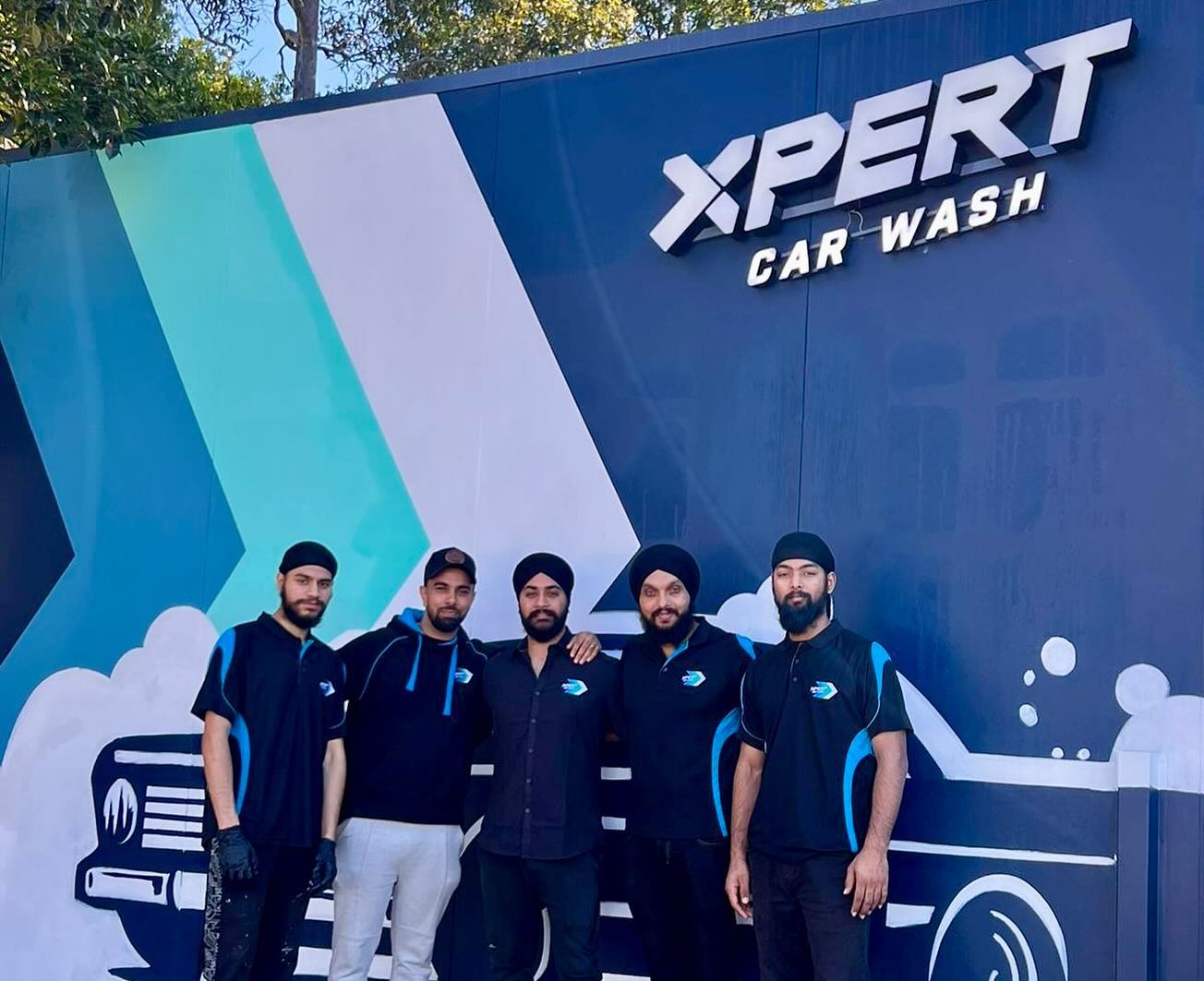 The Xpert Car Wash team in front of the Macquarie Park signage